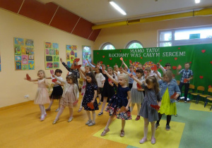 Dzieci tańczą z papierowymi sercami.